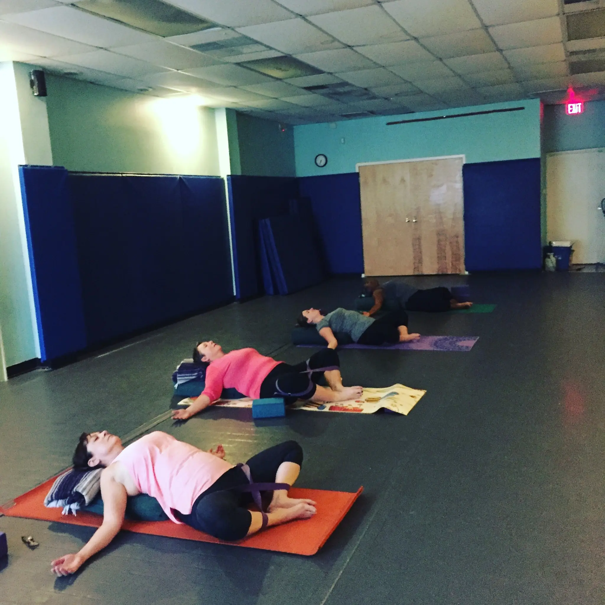 Students resting in a supported reclining pose during a mindfulness class at Palm Yoga in Tampa