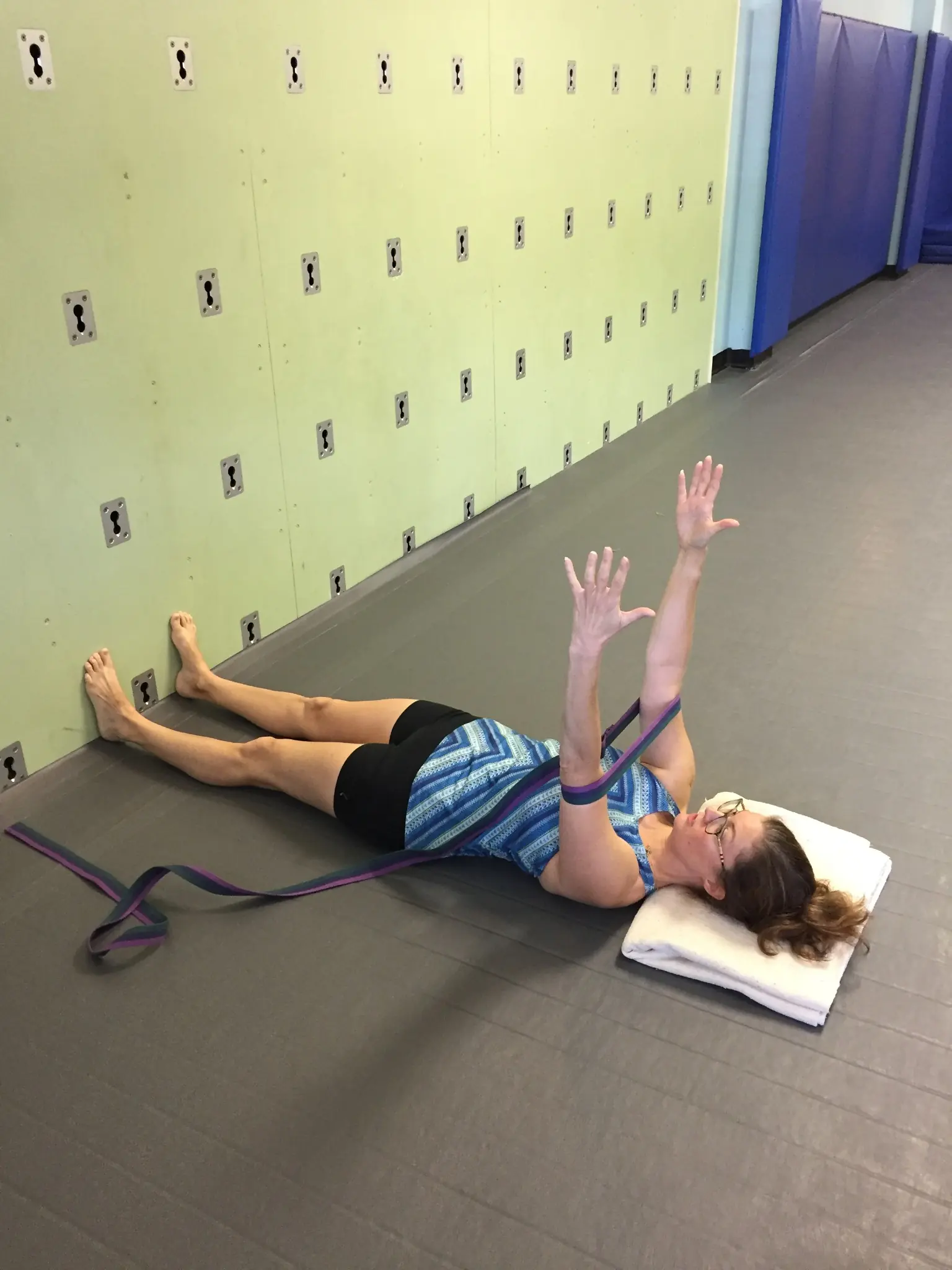 A student in a strap-supported reclining stretch with feet at the wall at Palm Yoga in Tampa