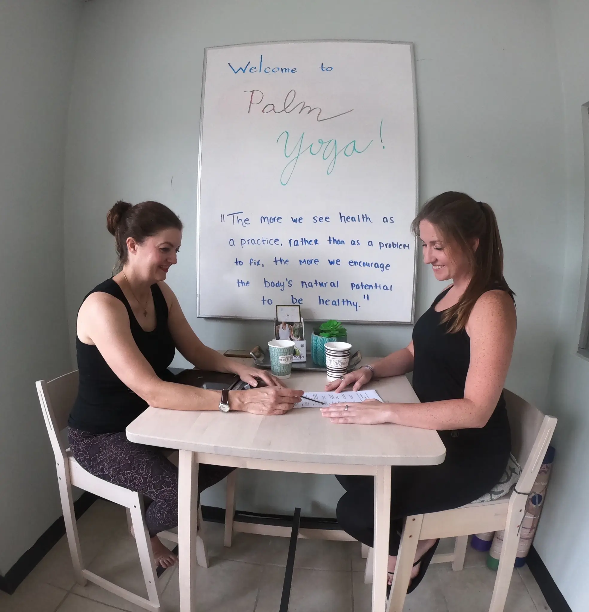 A new student reviewing class options with a teacher at the welcome desk at Palm Yoga in Tampa